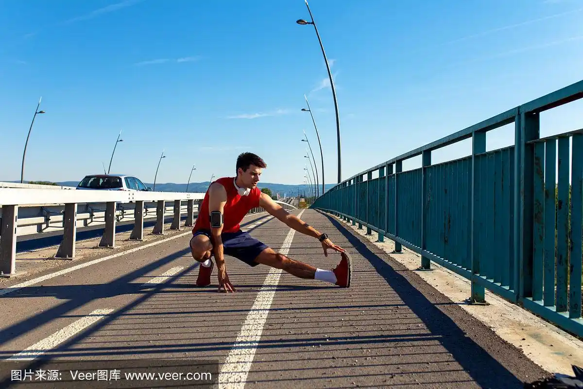 在阳光明媚的日子里,年轻的运动员在桥上跑步前伸展肌肉.