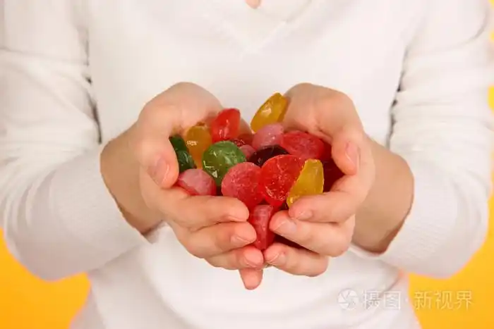 手里的糖果在黄色背景上