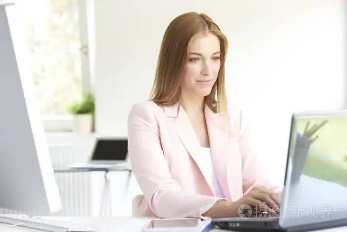 年轻漂亮的金融助理女商人坐在办公桌前工作膝上型电脑