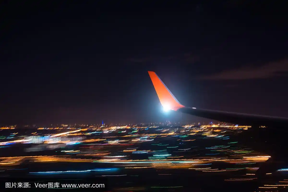 夜间迫降机场上空城市带灯光,观察机翼上的飞机,用长时间曝光拍摄