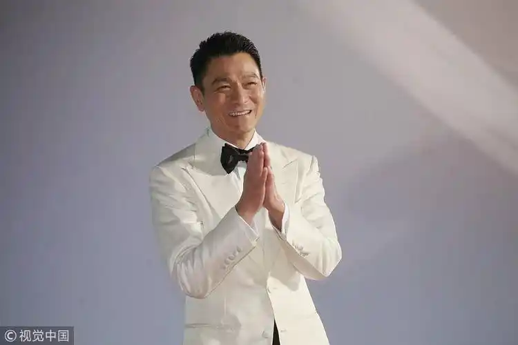 天王刘德华走上红毯,步伐充满活力,一身白色西装帅气十足,今晚他凭