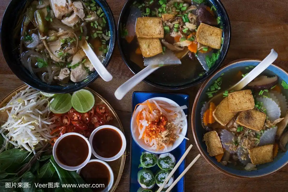 传统的越南菜.汤,面包卷和新鲜香草.木板表面上的盘子.