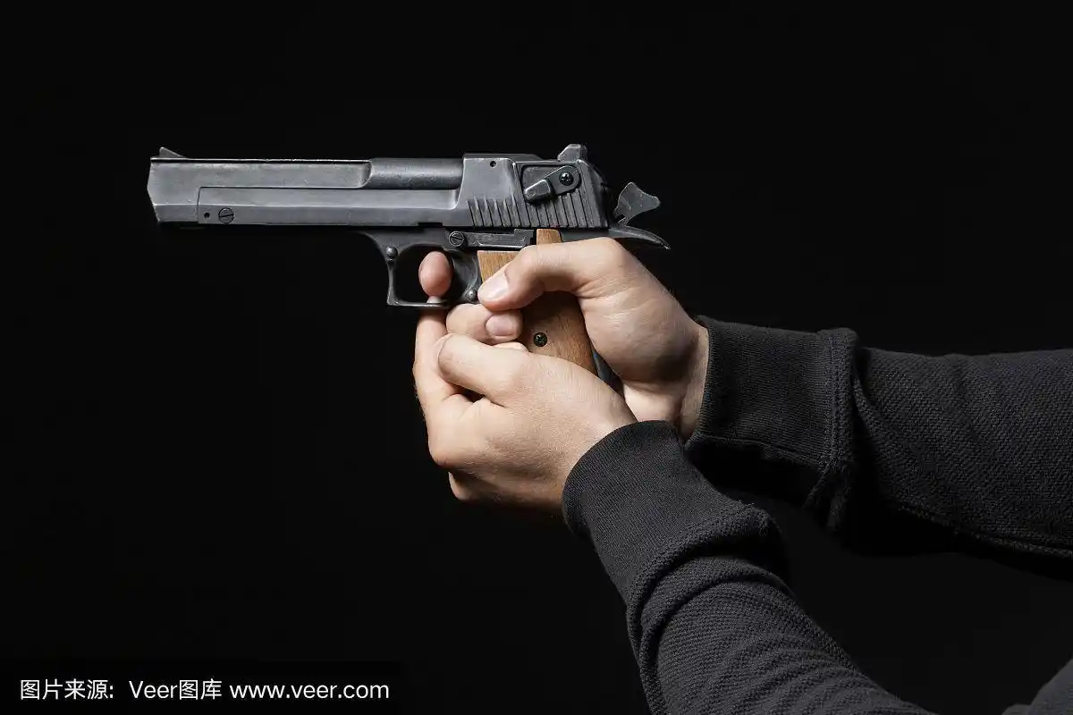 黑色背景下,男性手拿枪