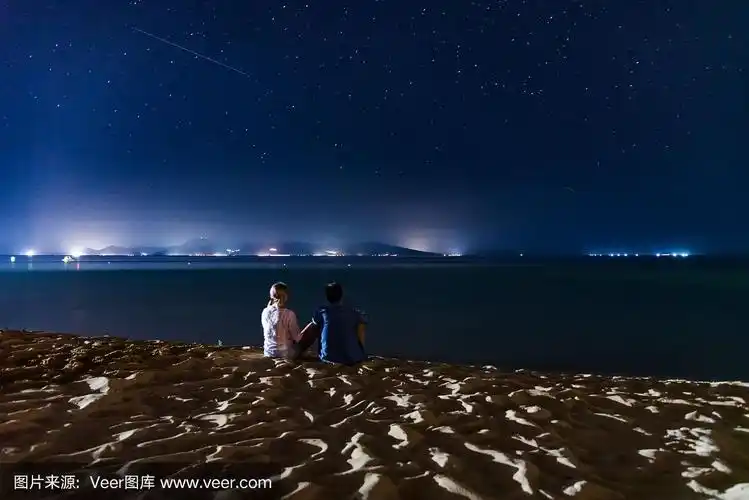 情侣们晚上在海滩上看星星点点的夜空.