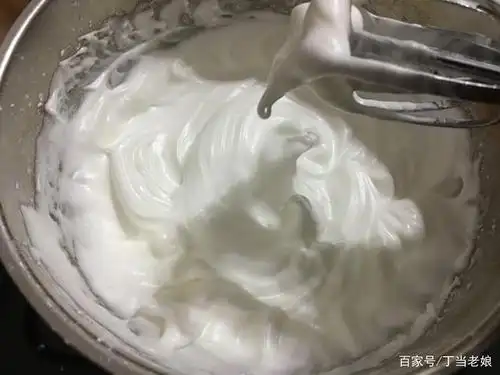 五,烤盘里铺上一张油纸,将打发好的蛋白霜放入,用刮刀抹成半圆状.