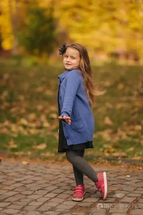 秋天公园里小女孩的肖像女孩模特向摄影师摆姿势愉快的孩子