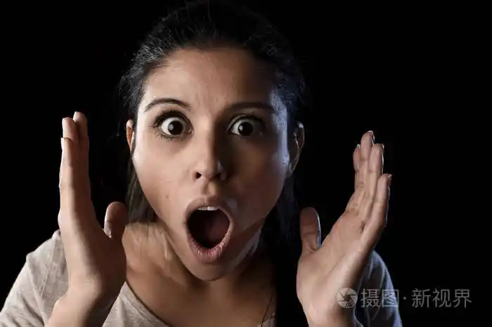 年轻美丽的害怕西班牙女人震动和惊讶的表情上黑色孤立