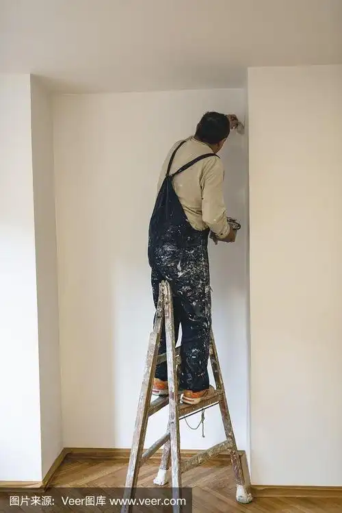 房屋油漆工正在用油漆刷刷白墙