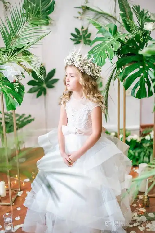照片 可爱的小女孩, 金发碧眼的卷发在白色的婚纱礼服和花圈的花朵