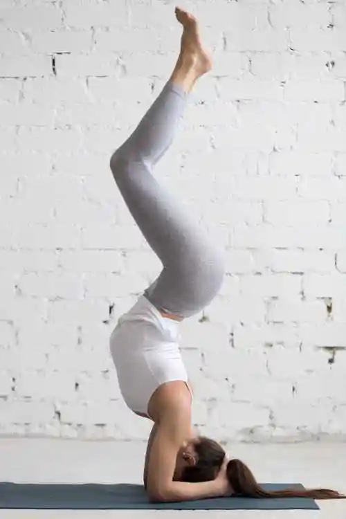 年轻漂亮的女人倒立瑜伽姿势