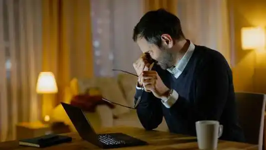 疲惫的中年男人在用笔记本电脑工作.