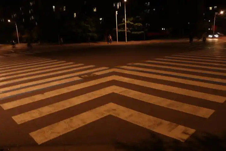 十字路口的斑马线向左右延伸,中间有行人车辆匆匆路过