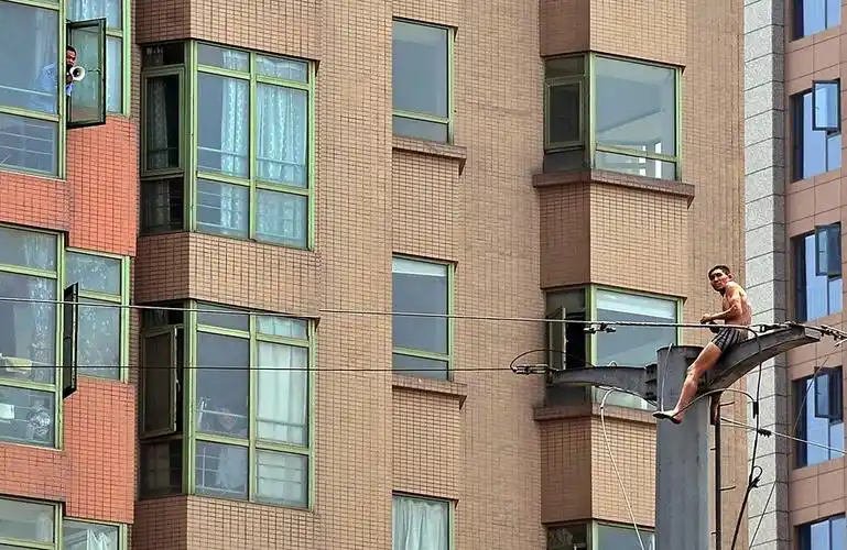 12013年5月27日,陕西西安,一名只穿着短裤的男子坐在电线杆上.