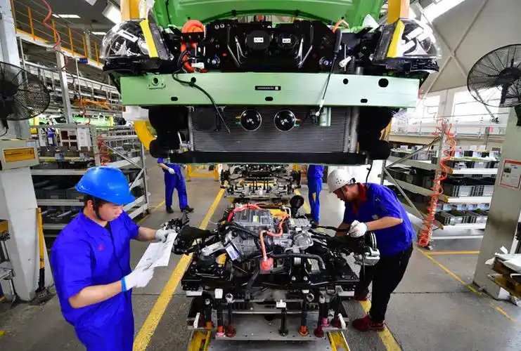 6月12日,工人在比亚迪西安基地总装车间准备为一辆新能源汽车安装电机