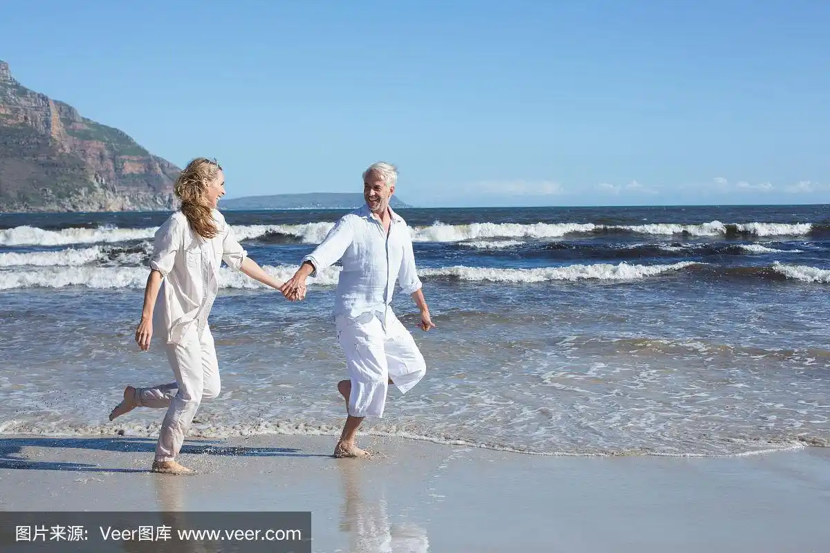 一对快乐的情侣在沙滩上赤脚跳绳