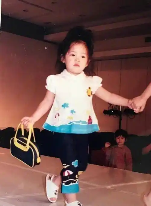 欧阳娜娜在被工作人员牵着手一起走路,穿着小裙子的欧阳娜娜十分可爱