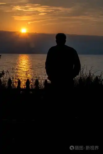 一个男人花时间看密歇根湖的日落, 享受和平与安宁.