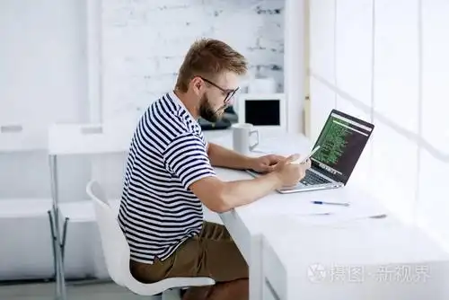 年轻人拿着笔记本电脑坐在办公桌上照片-正版商用图片10fpzy-摄图新