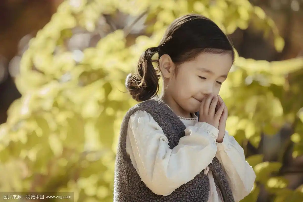 小女孩在秋天闭上眼睛祈祷的照片
