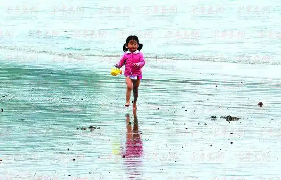 5月18日,第一海水浴场,一个小朋友光着脚丫在海滩上来回奔跑嬉戏.
