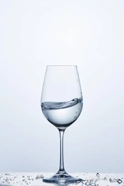 而站在有水的玻璃杯葡萄酒杯纯净水波气泡光背景