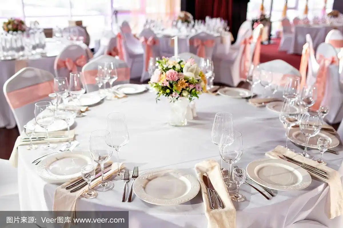 豪华婚宴上的圆桌.桌子上有漂亮的花.端盘子,玻璃杯子,服务员工作