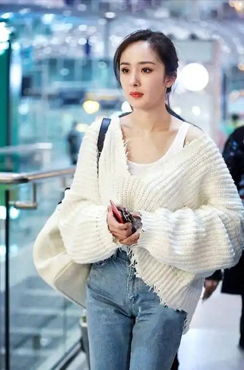 杨幂的上衣是由毛衣和背心搭配的,毛衣和背心都是同一个色系,白色系