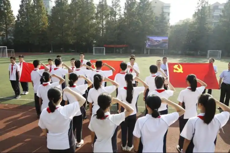 行知中学党员教师,共青团员和少先队员们高唱国歌,向国旗敬礼,共同