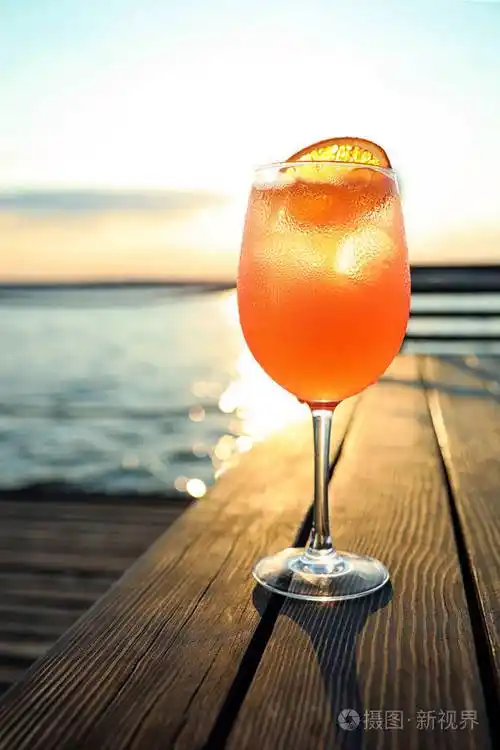 日落时在户外的木桌上放一杯新鲜的夏日鸡尾酒