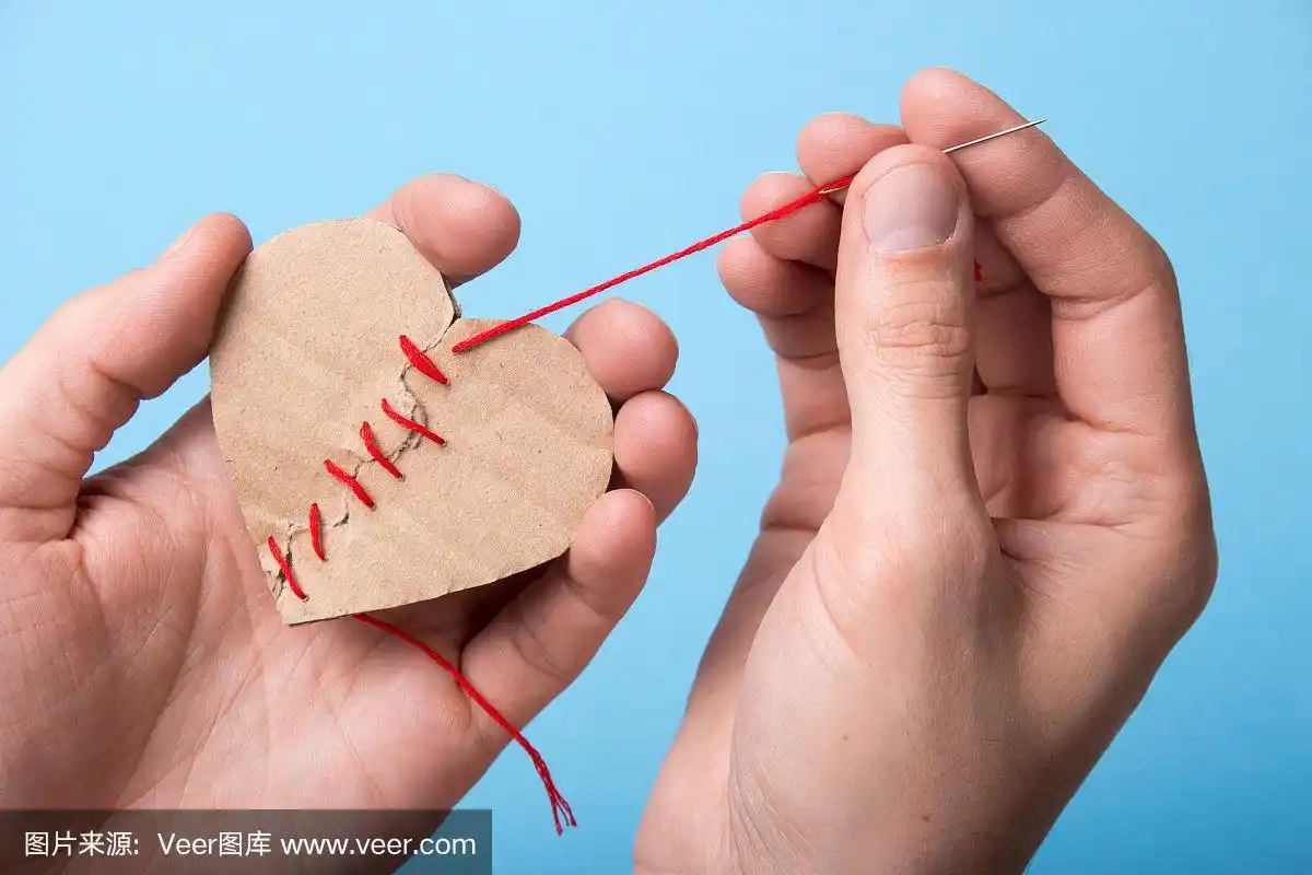 纸心的两半的一个人用针缝线在他的手上