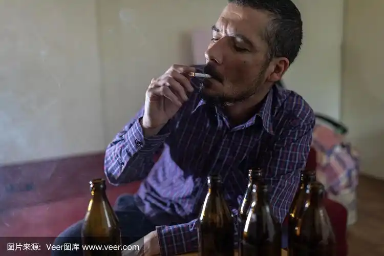 年轻悲伤的醉酒男子喝啤酒和酒精感到浪费,孤独和绝望