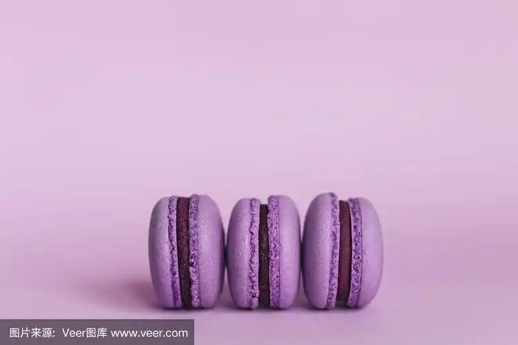 紫色背景上的三个法国马卡龙.文本.