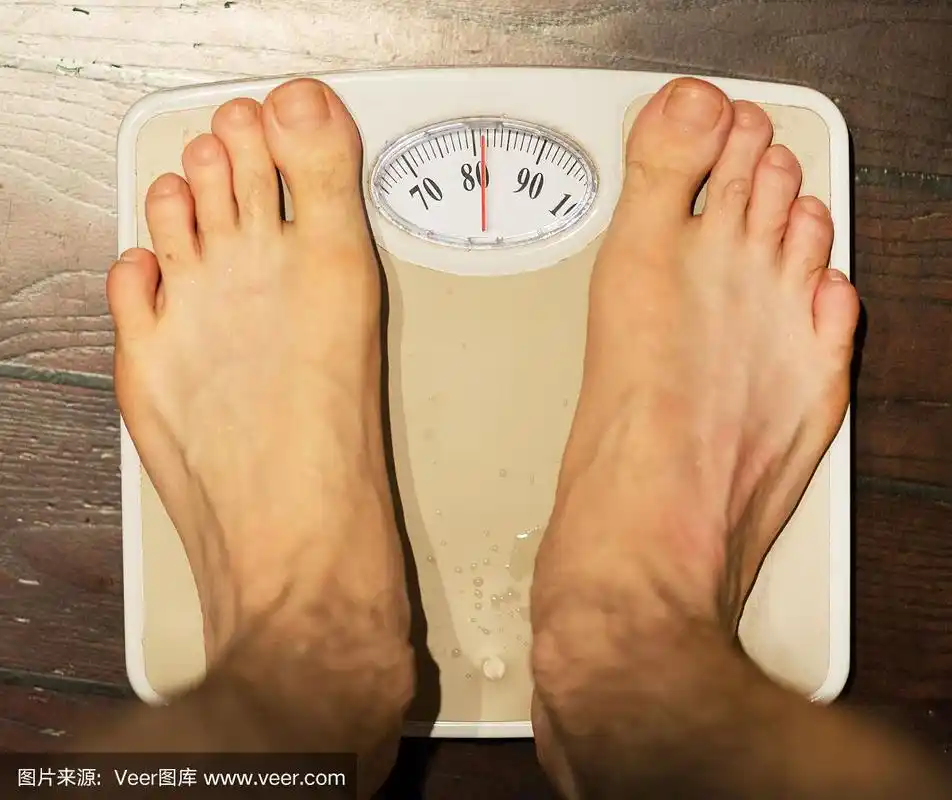 男人站在浴室的秤上.约80公斤.