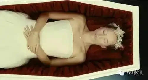 镜头切换,新娘躺在棺材里,棺木缓缓地合上,葬礼正在进行.