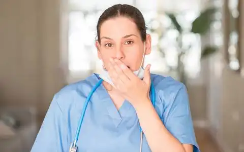 年轻的护士妇女戴口罩和听诊器捂嘴用手震惊的错误, 表达恐惧, 害怕在