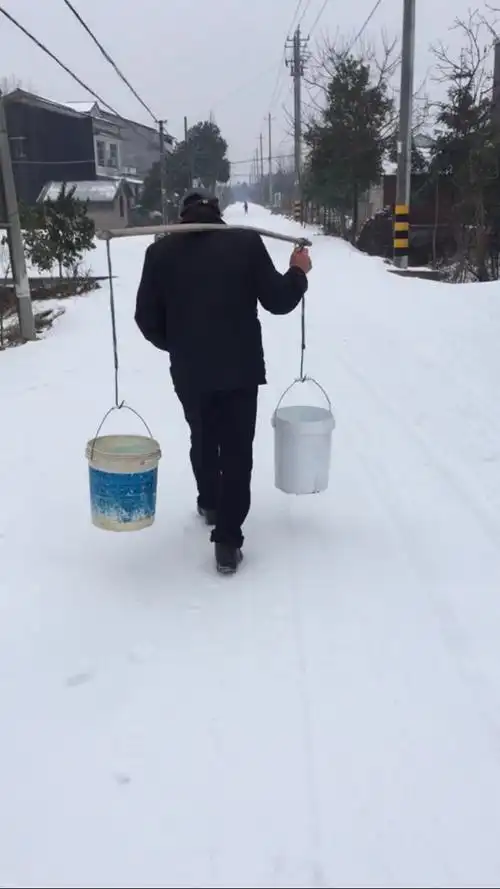 雪大了,爷爷顶着刺骨的寒风,扛着扁担去邻居家挑水.