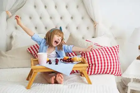 活的东西可爱的小女孩在床上吃东西打哈欠照片