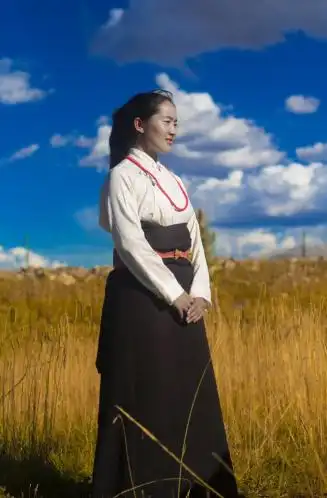 索南穿着传统藏袍站在草原上.