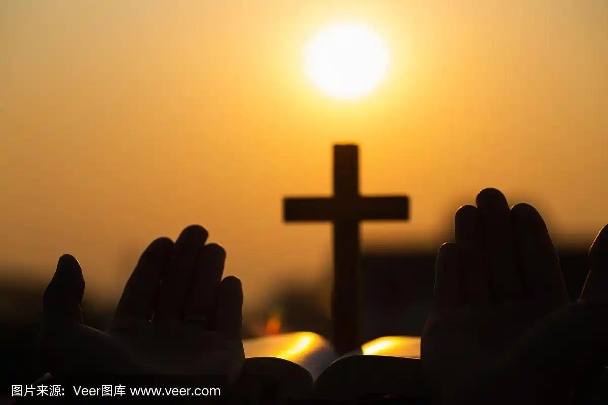 日出时,年轻女子用十字架和圣经祈祷的剪影,基督教概念背景.