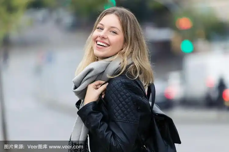 迷人的微笑年轻女子看着镜头在街上.