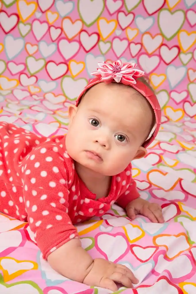 头巾的小女孩,可爱的宝宝的女孩穿着红色的头带与装饰的花,躺在遮蔽与