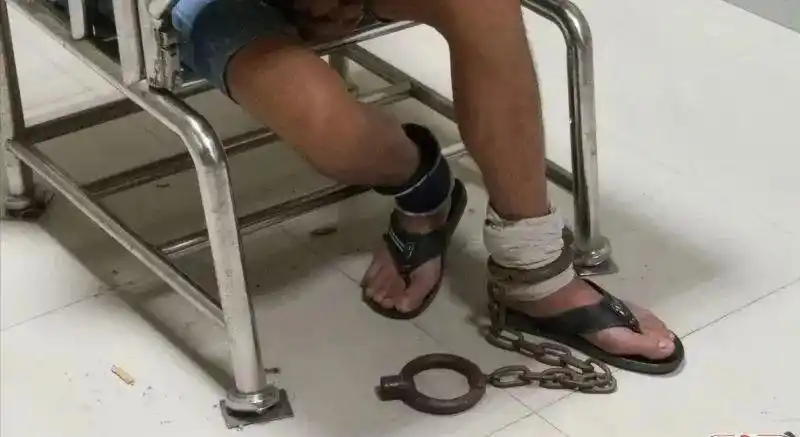黄某(外号阿十)被戴上脚镣.