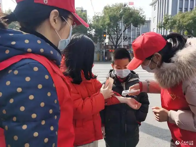 崇川区虹桥街道桃坞路社区志愿者尚伟正在为进入辖区的居民测量体温.