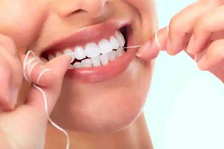 白色背景下女人伸出手指指着洁白健康的牙齿