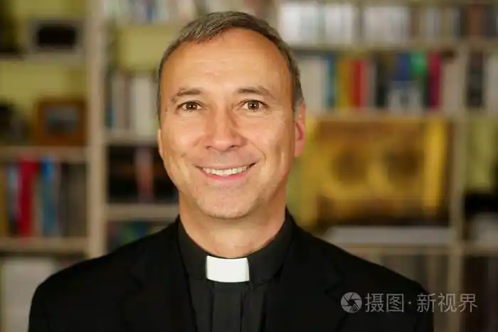 一个漂亮的微笑的天主教神父的肖像他用兴趣沉思而不失劝诱非洲皈依