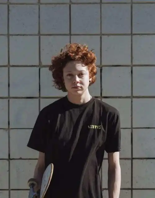 简单的黑色t恤,夹着一个滑板,将浓密的大波浪卷发剪短,虽然能够从一些