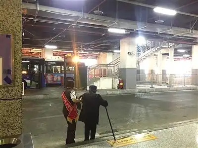 扶着一位拄着拐杖的老人,慢慢走过马路