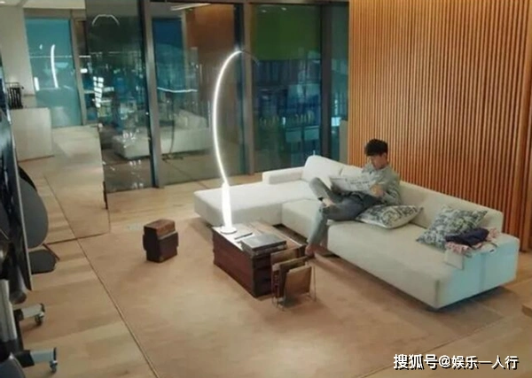 靳东家的客厅是非常的宽敞,背景为木色条形背景墙,地板采用的木质地板