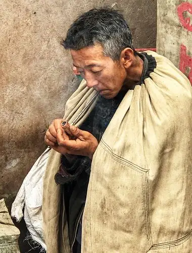 彝族男人都喜欢蹲在屋檐下,倚在土墙边,披着查尔瓦,抽着烟,喝着酒,聊