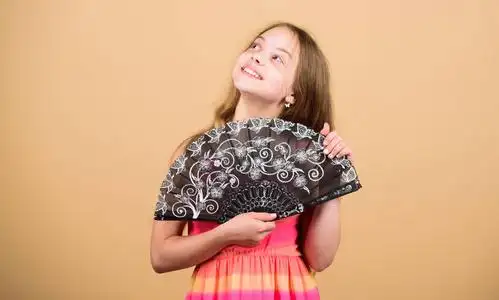 女孩用扇子扇风.空气循环.艺术与文化.手持式风扇创造气流.